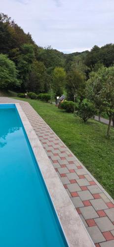 a swimming pool with a brick walkway next to a yard at VILA LASOVIC + POOL + JACUZZI + SAUNA in Tuhelj