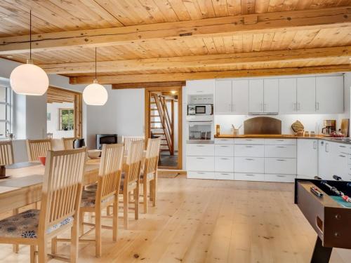 a kitchen and dining room with white cabinets and wooden ceilings at Holiday Home Åsta - 400m to the fjord by Interhome in Roslev
