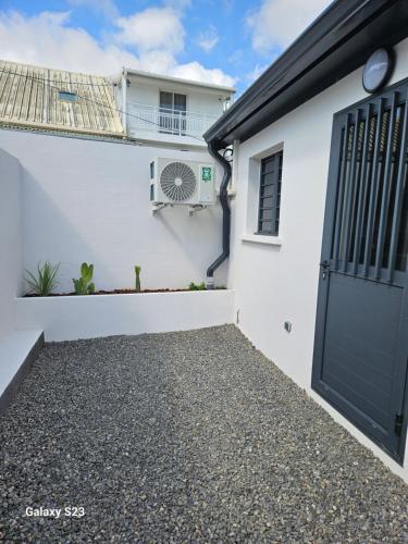 a white house with a black garage door at La KAZ SAMANY in Sainte-Suzanne