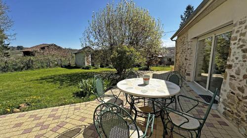 a table and chairs on a patio with a yard at Fayollas in Bussière-Galant