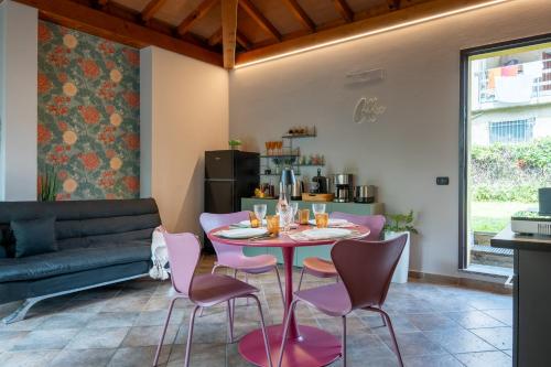 a dining room with a table and pink chairs at Da Gise Giardino Wifi Malpensa in Somma Lombardo