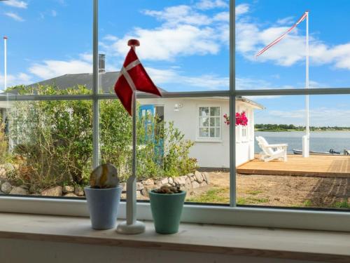a window with a view of a house with a flag at Holiday Home Jorek - 10m to the fjord by Interhome in Munkebo