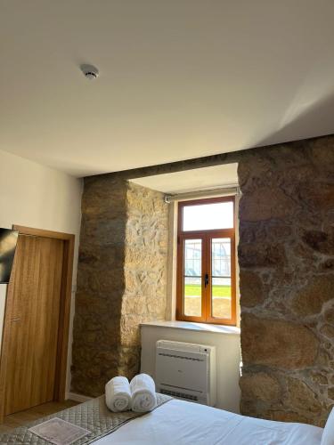 a bedroom with a stone wall with a bed and a window at Palacium Charming Suites in Figueiró dos Vinhos