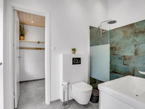 a white bathroom with a toilet and a sink at Holiday Home Apelone - 900m from the sea by Interhome in Marielyst