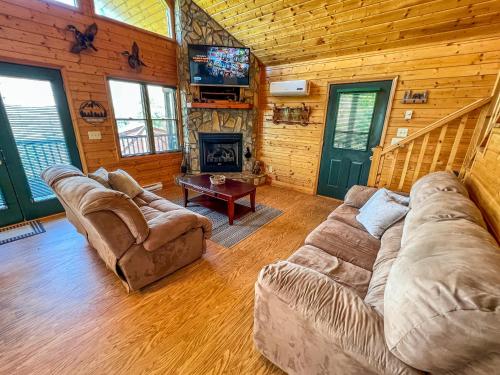 a living room with couches and a television in a cabin at Logged Out in Piney Creek