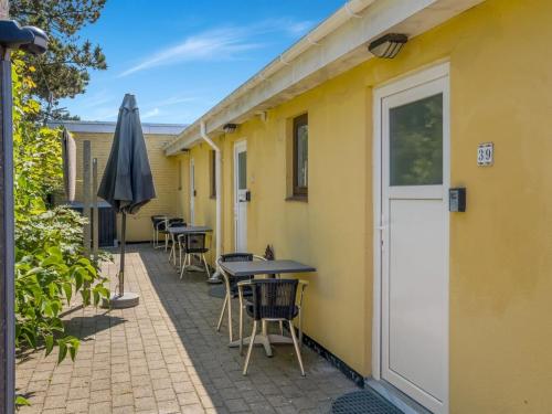 een terras met tafels, stoelen en een parasol bij Apartment Sibyll - 2km from the sea by Interhome in Skagen