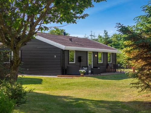 a black house with a porch and a yard at Holiday Home Laris - 700m to the inlet by Interhome in Løgsted