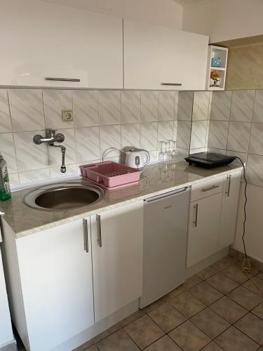 una cucina con mobili bianchi e un lavandino di Tami Apartment a Novi Sad