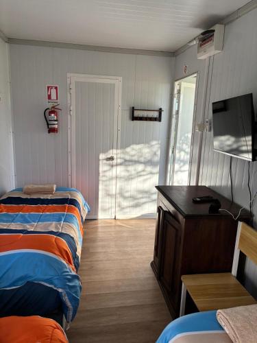 a room with two beds and a tv and a door at La Martinna 3 in Trinidad