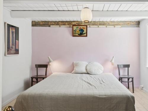 a bedroom with a bed with two chairs at Holiday Home Aarni - 6-5km from the sea by Interhome in Gudhjem