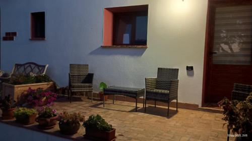 a patio with three chairs and potted plants at Su Saucu in Dorgali
