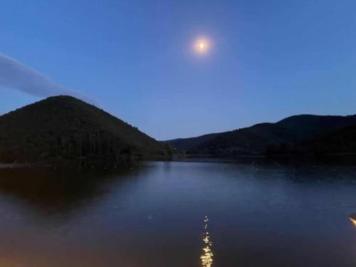 a moon rising over a lake at night at Casa MARIAM - la tua casa nel cuore di Piediluco in Piediluco