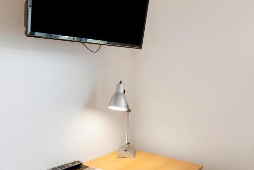 a lamp on a desk with a television on a wall at Ferienwohnung Eichenauer in Angersbach