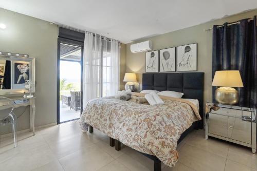 a bedroom with a large bed and a balcony at Villa Blanca in Case-Pilote