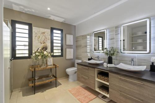 a bathroom with two sinks and a toilet and mirrors at Villa Blanca in Case-Pilote