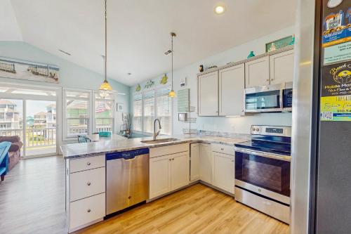 a kitchen with white cabinets and stainless steel appliances at Turtle Cove in North Topsail Beach