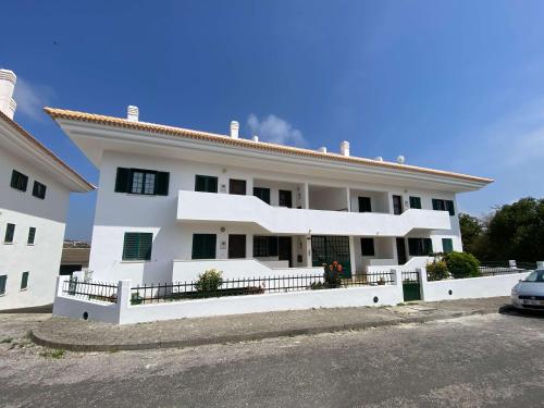 a white house with a car parked in front of it at Apartment Wolf in Lourinhã