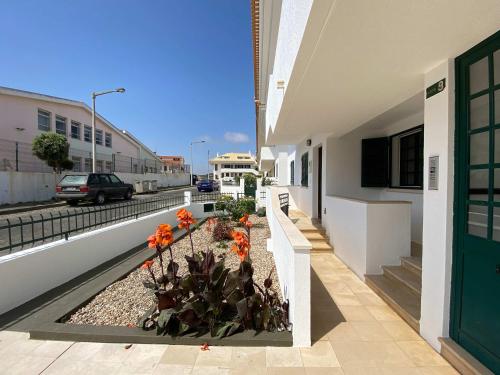 a building with a green door and flowers on the sidewalk at Apartment Wolf in Lourinhã