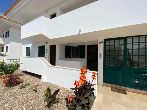 a white house with a green door and some flowers at Apartment Wolf in Lourinhã