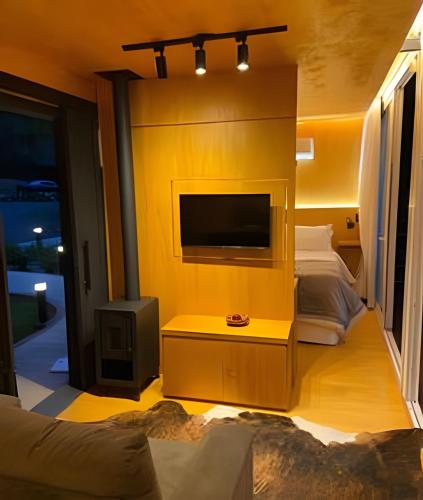 a living room with a tv and a yellow wall at HOSPEDE-SE EM UM CONTAINER AO LADO DE GRAMADO - RS in Igrejinha