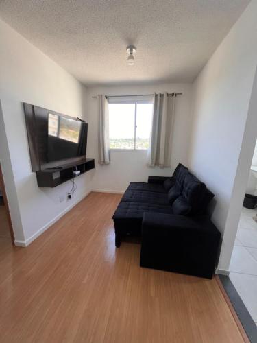 a living room with a black couch and a flat screen tv at Ap em ótima localização in Cuiabá