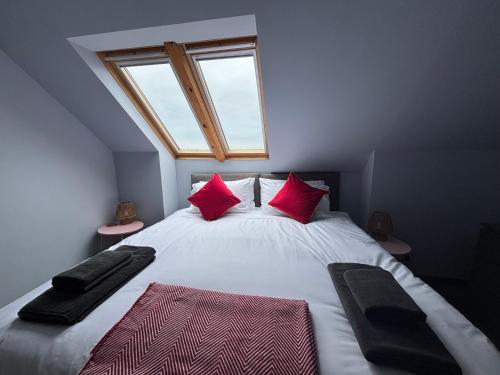 a bedroom with a bed with red pillows and a window at Vestley Banks in Orkney