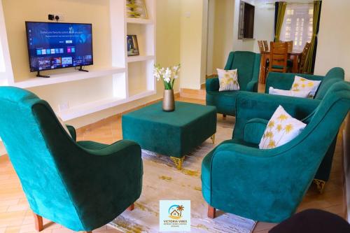 a living room with green chairs and a flat screen tv at Victoria Vibes Retreat in Kisumu