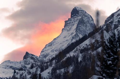 a mountain covered in snow with a colorful sky at Le Mirabeau Resort & Spa in Zermatt