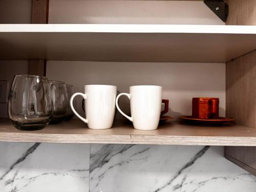 three white coffee mugs sitting on a shelf at Monoambiente a estrenar ubicado en el centro de la Falda in La Falda