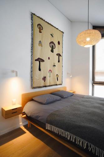 ein Schlafzimmer mit einem Bett und einem Gemälde an der Wand in der Unterkunft N i d e l ê in Nida