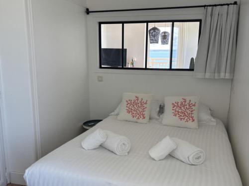 1 cama blanca con 3 almohadas y ventana en Le Balcon de Tresmeur, en Bonne Nouvelle