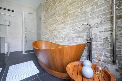 baño con bañera de madera y pared de ladrillo en Luxury 3 Bedrooms Apt near Hilton hotel, en Tel Aviv