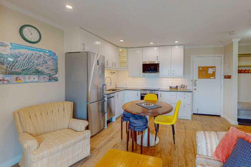 a kitchen with a table and yellow chairs in a kitchen at Snow Ghost Inn 326 in Big White