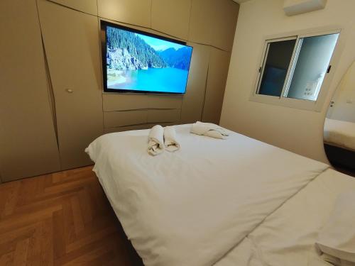 a bedroom with a white bed with a flat screen tv at Yalarent C Kinneret Amazing Apartments in Migdal