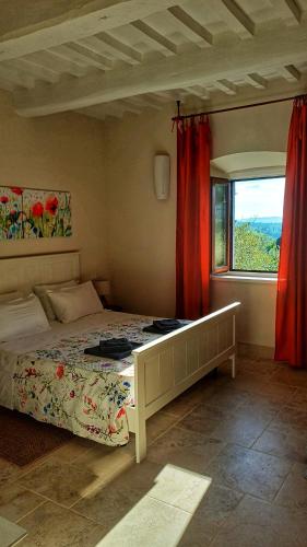a bedroom with a bed and a window with red curtains at Il Sensalino in San Donato in Poggio