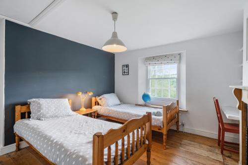 a bedroom with two beds and a desk and a window at Treovis Farm in Callington