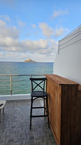 a black chair sitting on a balcony looking out at the ocean at Dream View Luxe in Rafrāf