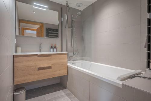 a bathroom with a tub and a sink and a mirror at Senna - Center Les GETS spacious & modern in Les Gets