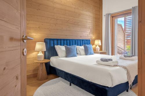 a bedroom with a blue and white bed and a window at Senna - Center Les GETS spacious & modern in Les Gets