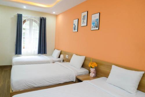 two beds in a room with orange walls at Tina's House & Spa - Sunset Town Phu Quoc in Phu Quoc