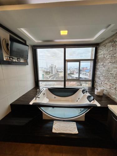 a bath tub in a bathroom with a large window at Hotel Oceanik in Manta