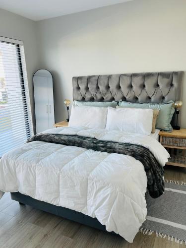a bedroom with a large bed with a gray headboard at 27D Homestead View in St Francis Bay