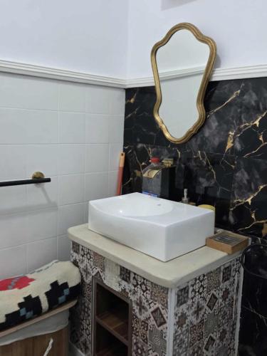a bathroom with a white sink and a mirror at Jolie appartement h standing s plus 2 in Shanīnī