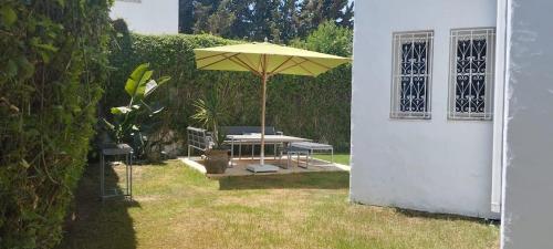 un patio avec un parasol, une table et des chaises dans l'établissement VILLA de CHARME A HAMMAMET TUNISIE, à Hammamet