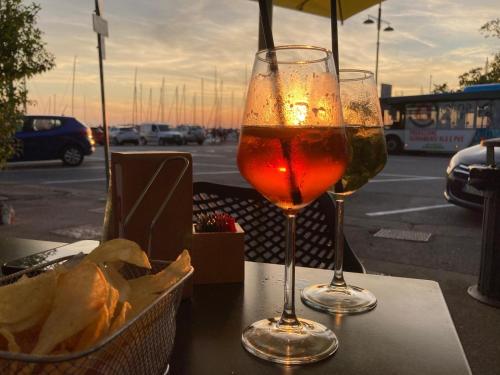 two wine glasses sitting on a table with a basket of chips at Il Giardino Nascosto in Trieste