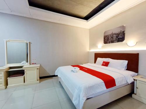 a bedroom with a large bed and a mirror at Hotel Istana Syariah Pekalongan by Hello Room in Pekalongan