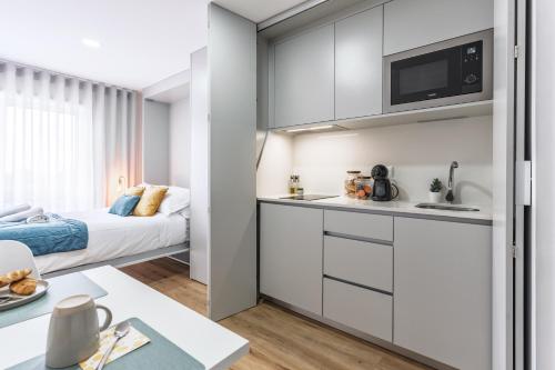a kitchen with white cabinets and a bed in a room at Lotus in Aveiro