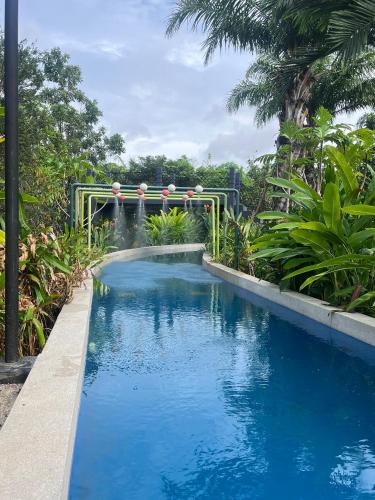 a swimming pool in a garden with a waterfall at GREENHILLS RESORT Si Racha in Ban Nong Wa