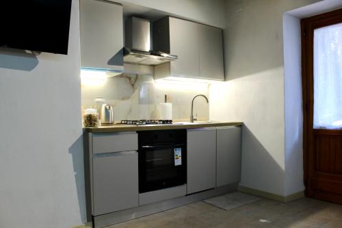 a kitchen with white cabinets and a stove top oven at Sogni sul Lago - Passignano sul Trasimeno in Passignano sul Trasimeno