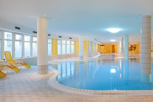 a large swimming pool in a building with chairs at Dorint Seehotel Binz-Therme in Binz